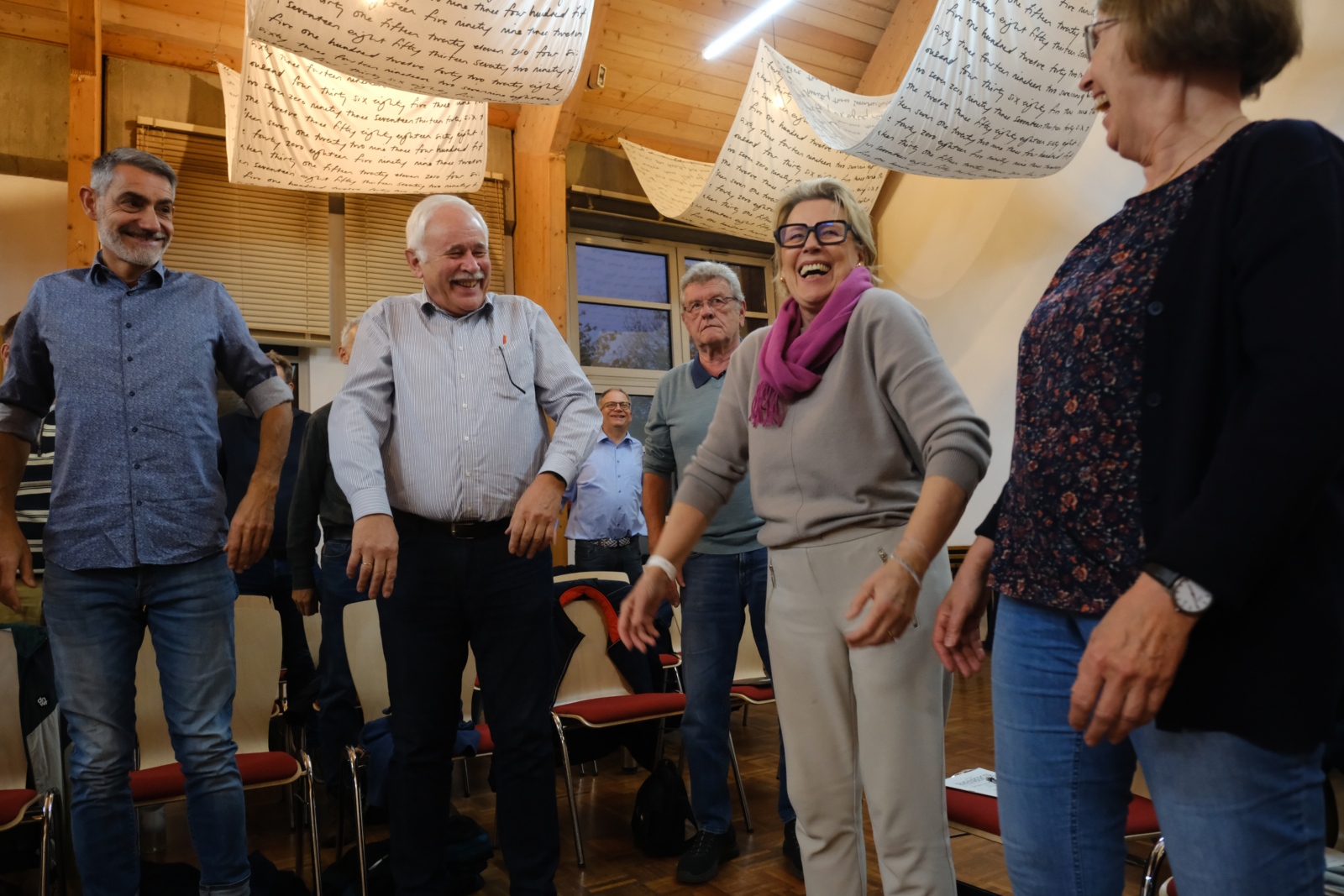 Ein Foto zeigt zwei Frauen und drei Männer die im Kreis stehen und lachen.