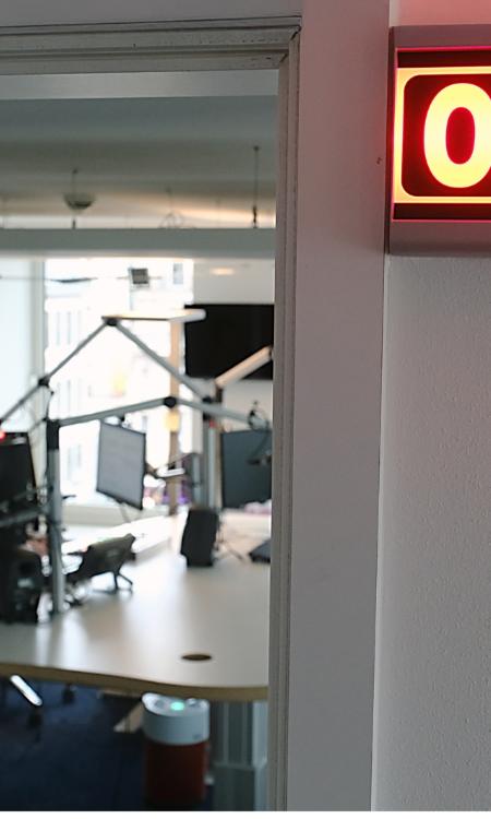 Ein Foto zeigt den Blick in das Radiostudio von Domradio. Vor dem Studio leuchtet ein Schild mit der Aufschrift On Air.