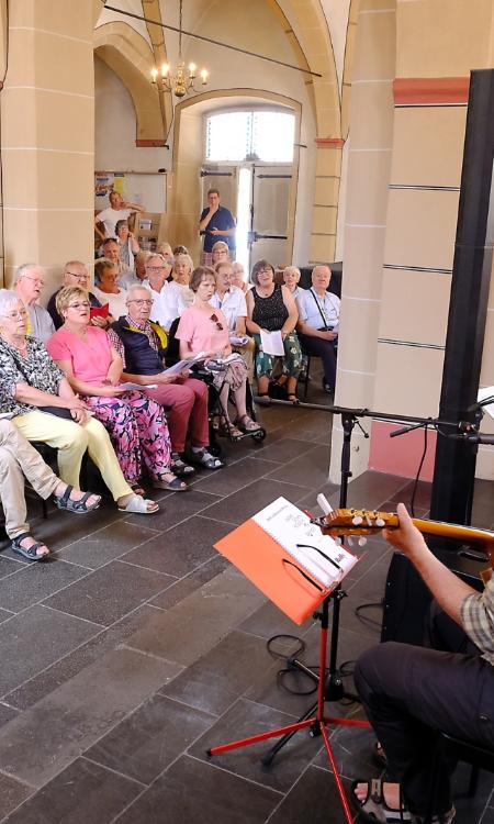Ein Foto zeigt zwei Männer mit Gitarren vor Publikum in einer Kirche.