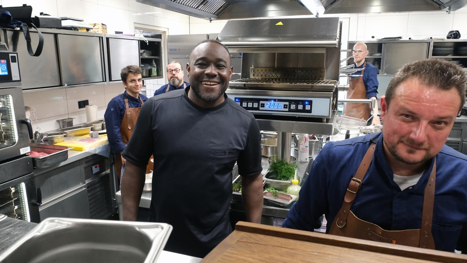 Ein Foto zeigt den Blick in eine Restaurantküche, in der Nelson Müller mit vier Köchen steht.