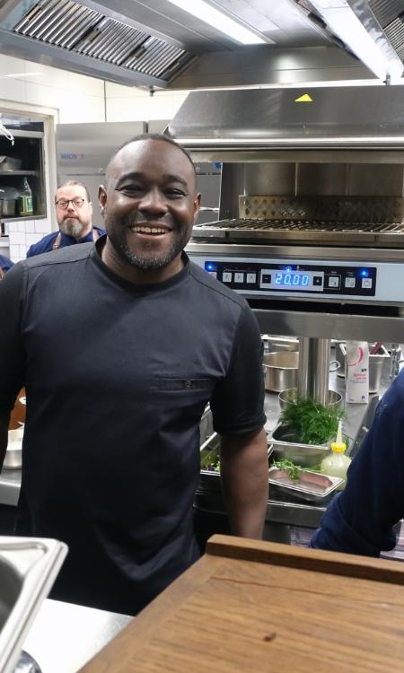 Ein Foto zeigt den Blick in eine Restaurantküche, in der Nelson Müller mit vier Köchen steht.