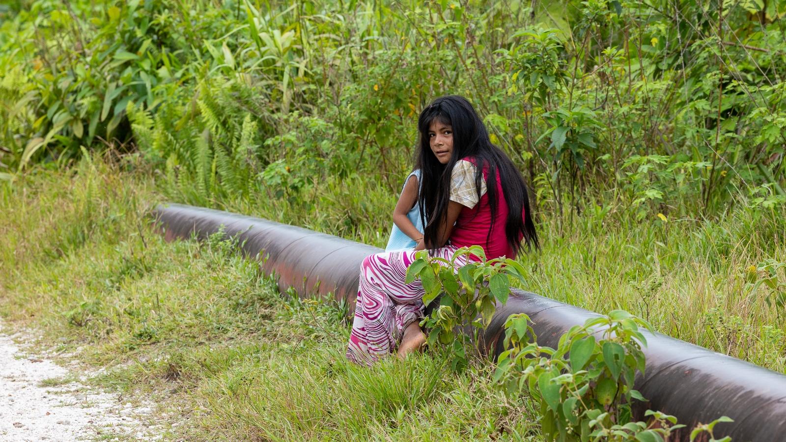 Ein Foto von einem Mädchen, das auf einer Pipeline sitzt vor grünem Hintergrund.