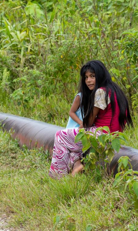Ein Foto von einem Mädchen, das auf einer Pipeline sitzt vor grünem Hintergrund.
