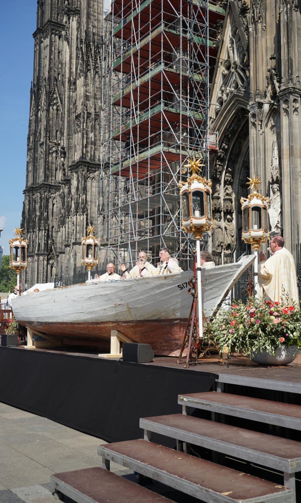 Ein Foto von einem Holzboot vor dem Kölner Dom, das als Altar für einen Gottesdienst genutzt wird.