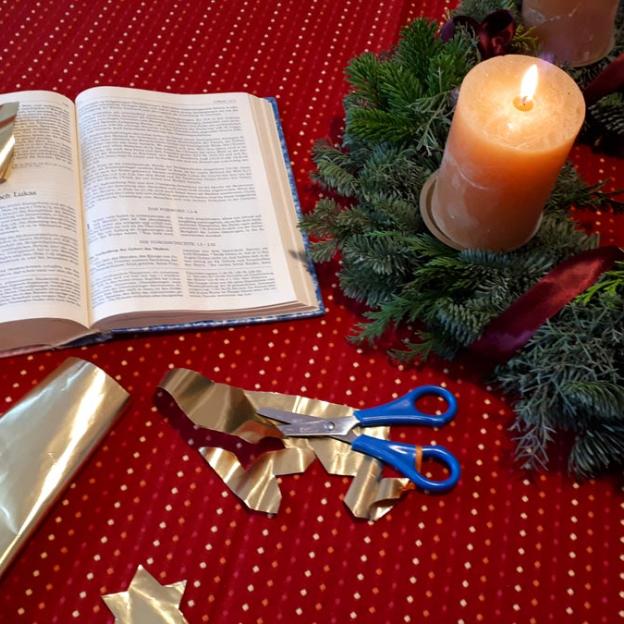 Adventtisch mit Kranz, Bibel, Schere und Goldpapier