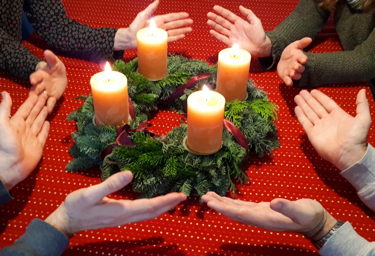 Segen-erbittende Hände um Adventskranz