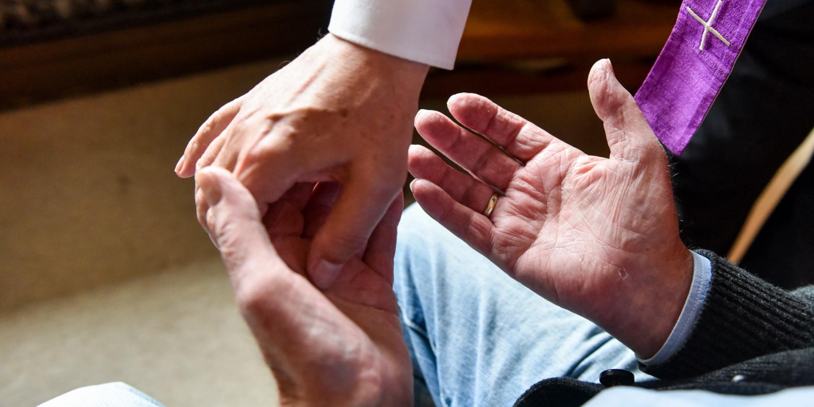 Ein Pfarrer besucht am 8. September 2017 in Bonn einen Kranken zu Hause in seiner Wohnung und spendet die Krankensalbung. Mit Salböl zeichnet der Priester ein Kreuz in die Handflächen des Mannes.